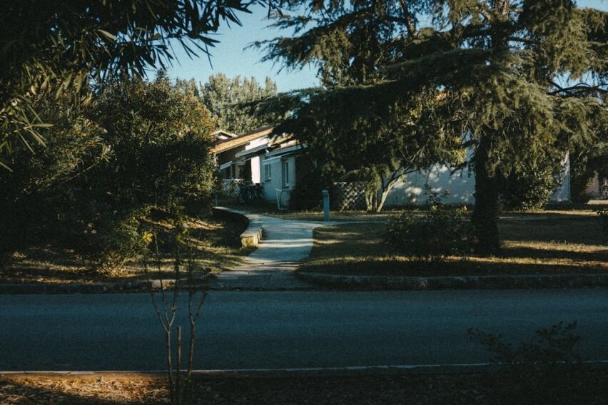 Sunny, clean suburban street that splits into a fork in the road, symbolizing the choice a homeowner faces between differe...