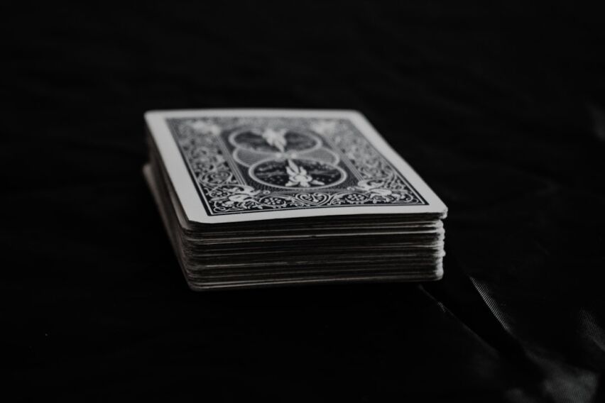 Carefully constructed house of playing cards looking unstable on a bright, clean background, symbolizing the fragile myth ...
