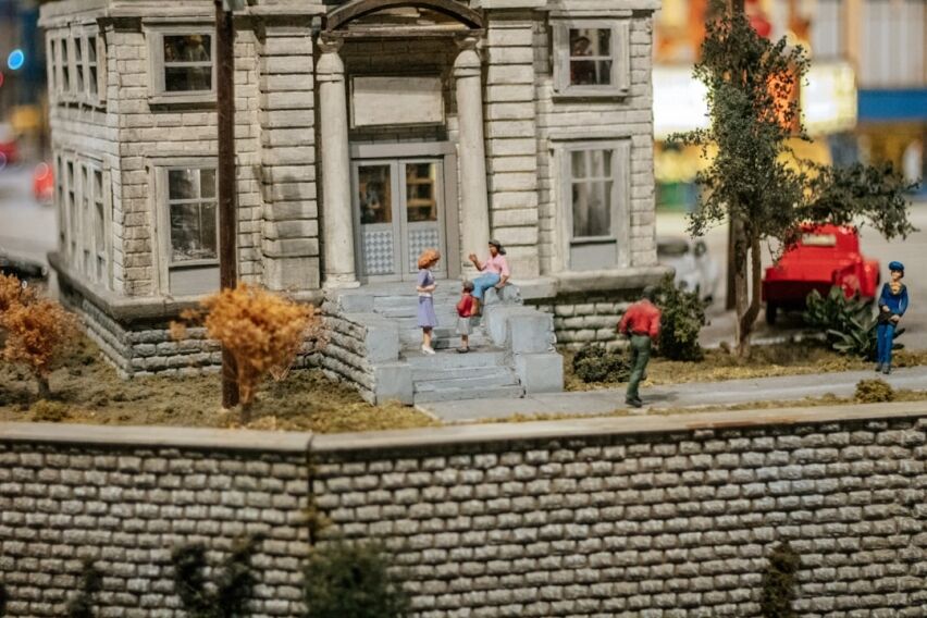 Close-up, professional shot of a person using a magnifying glass to scrutinize a small model of a house, symbolizing a clo...