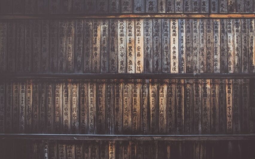 Close-up of a dusty stack of old VHS video cassettes on a shelf, symbolizing an outdated and obsolete business model.