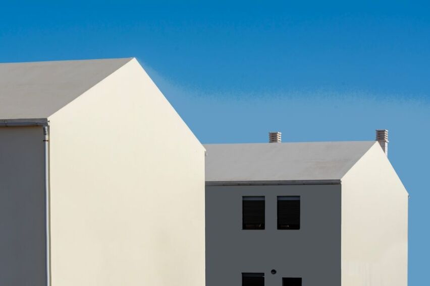 Modern, minimalist house with a long, dramatic shadow cast across it, symbolizing the hidden costs of shadow inflation in ...