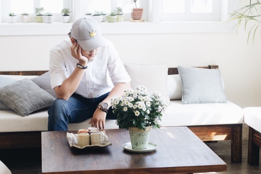 Person sits at a modern desk with a worried expression, using a calculator with house keys nearby, symbolizing the financi...