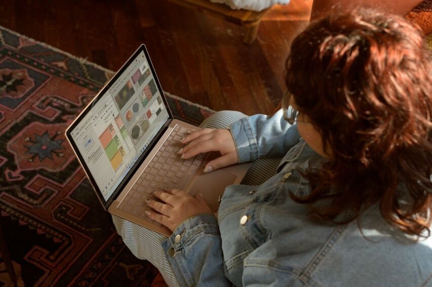 Person sits in a modern living room, using a tablet to navigate a virtual tour of a home, showcasing real estate technology.