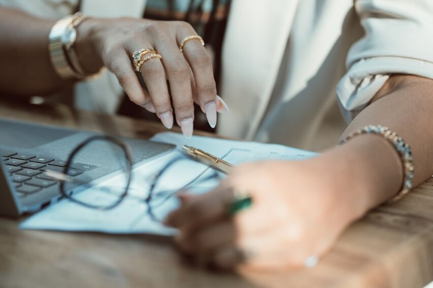 Homeowner sits at a modern desk, looking stressed and overwhelmed while reviewing a stack of financial documents and a cal...