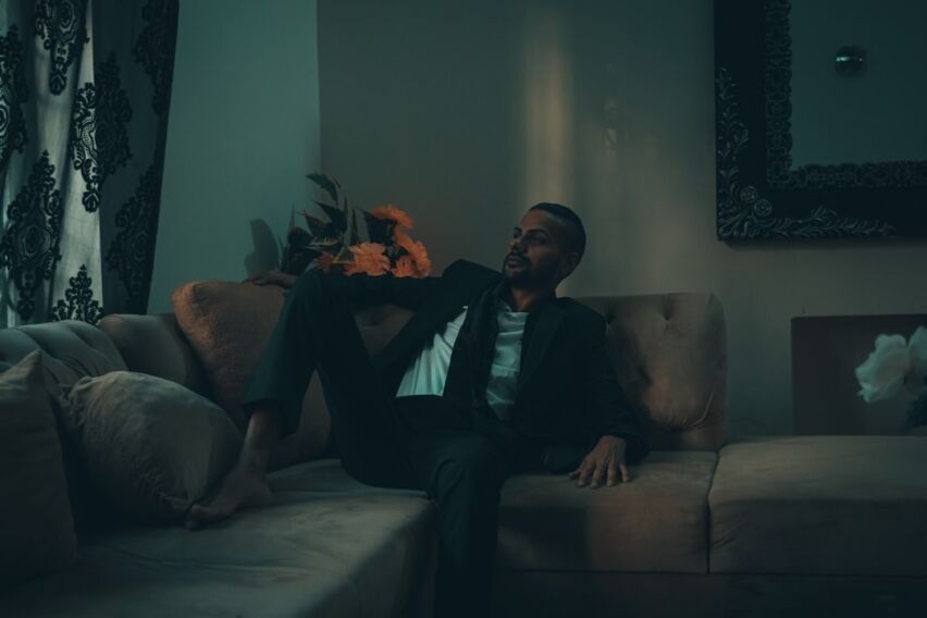 Professionally dressed person looking stressed while sitting in a minimalist, modern luxury living room, symbolizing the f...