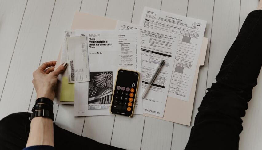 Professionally dressed person sits at a clean, modern desk, looking at a calculator with a stressed or concerned expressio...