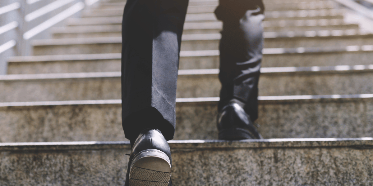 Businessperson walking up stairs that represent the steps to starting a real estate brokerage
