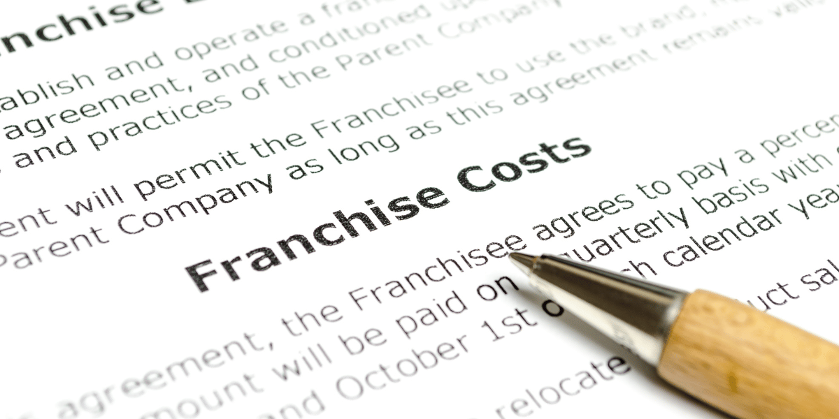 Pen set on top of a franchise agreement pointing to the franchise costs section.