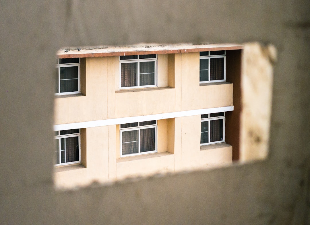 A magnifying glass held over a formal document next to a small architectural model of a house, representing the close inspection of a real estate contract.