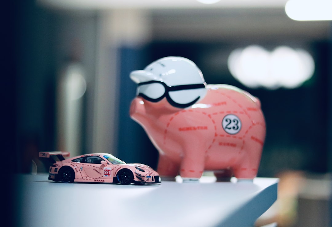 A minimalist photo showing a piggy bank placed next to a small model of a house on a bright surface, illustrating the concept of saving money on real estate commissions.
