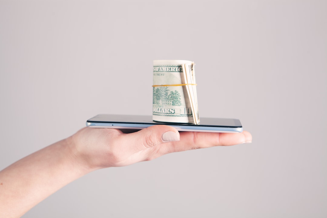 A minimalist photo of a hand removing a significant portion from a neat stack of money against a clean background, representing the large percentage taken by real estate fees.
