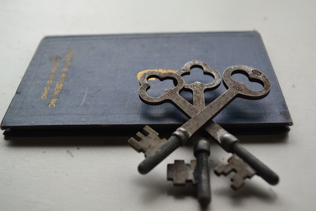 An old, ornate house key rests next to a sleek, modern smartphone on a clean, bright surface, contrasting outdated real estate traditions with new technology.