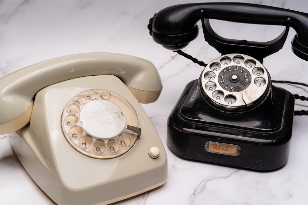 Vintage rotary telephone sits next to a sleek, modern smartphone on a clean surface, symbolizing technological evolution a...