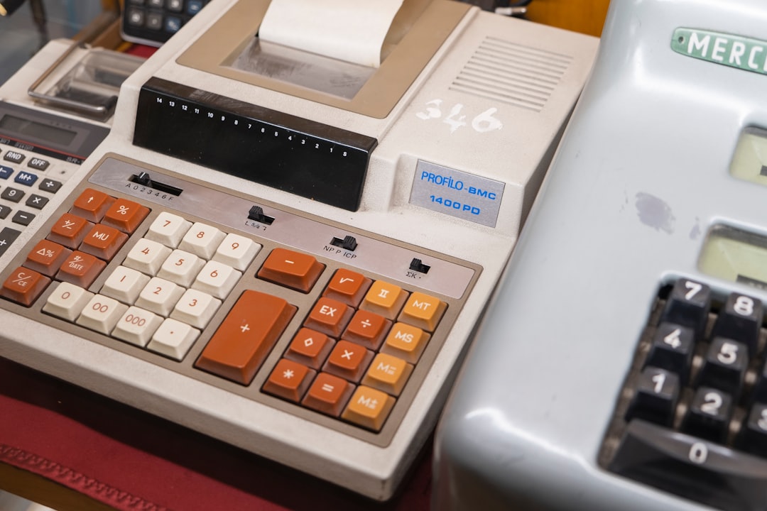 An old-fashioned calculator sits next to a set of sleek, modern house keys on a professional desk, contrasting an outdated financial model with modern home ownership.