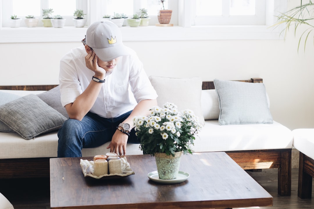 Person sits at a modern desk with a worried expression, using a calculator with house keys nearby, symbolizing the financi...