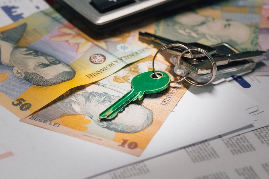 A set of modern house keys placed next to a sleek calculator on a bright, clean desk, representing the financial savings from real estate commissions.