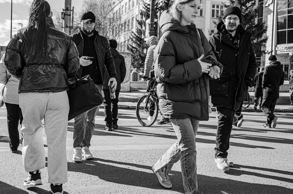 A single person walks in the opposite direction of a conforming crowd of business professionals, symbolizing the challenge of breaking from industry norms.