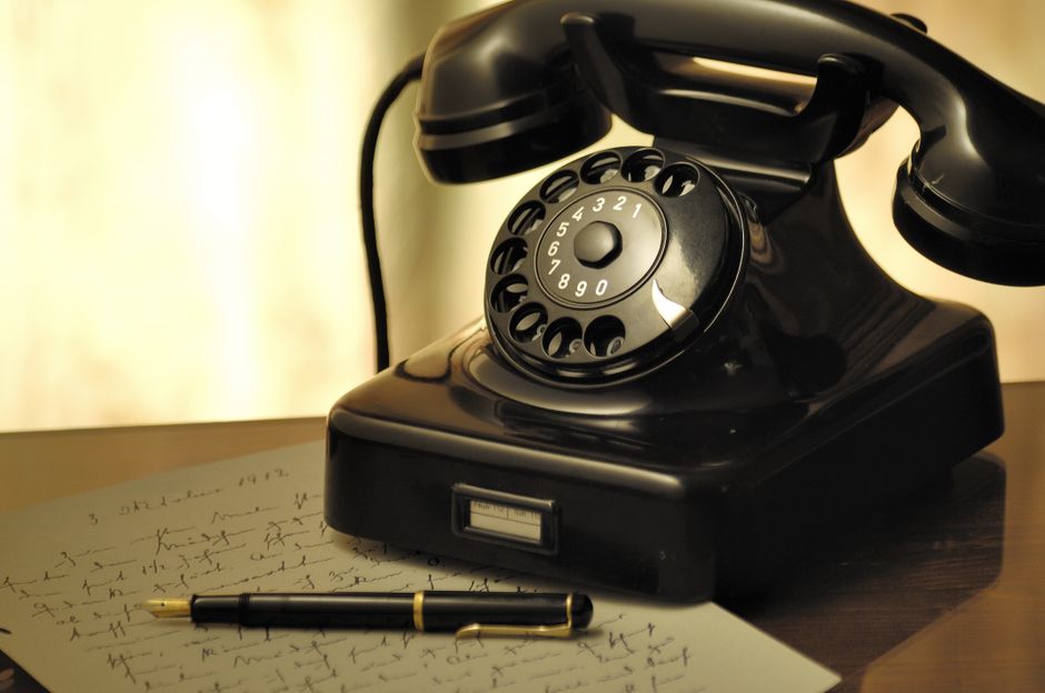 Vintage rotary phone and a modern smartphone sitting side-by-side on a clean surface, illustrating the contrast between ol...