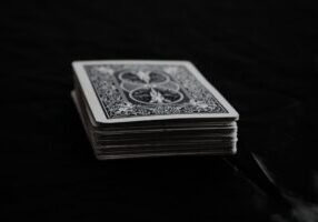 Carefully constructed house of playing cards looking unstable on a bright, clean background, symbolizing the fragile myth ...