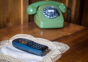 Classic black rotary phone sits on a clean, modern white desk, symbolizing an obsolete relic in a contemporary professiona...