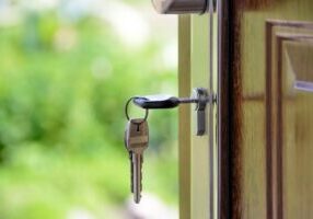 Confident person sits in their bright, modern living room, using a laptop to research real estate options and save money o...