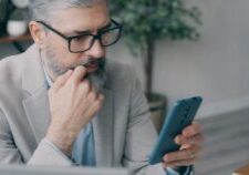 Homeowner looking concerned while reviewing a stack of official-looking documents at a clean, modern table, representing t...
