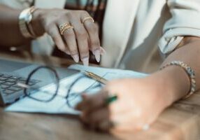 Homeowner sits at a modern desk, looking stressed and overwhelmed while reviewing a stack of financial documents and a cal...