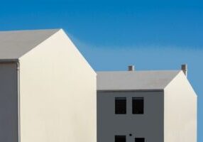 Modern, minimalist house with a long, dramatic shadow cast across it, symbolizing the hidden costs of shadow inflation in ...