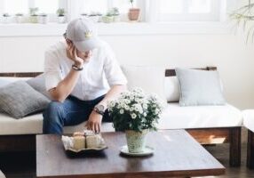 Person sits at a modern desk with a worried expression, using a calculator with house keys nearby, symbolizing the financi...