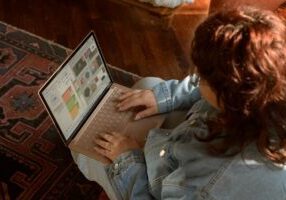 Person sits in a modern living room, using a tablet to navigate a virtual tour of a home, showcasing real estate technology.