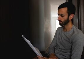 Person with a concerned expression reviews financial paperwork with a calculator, illustrating the stress of discovering h...