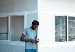 Professional person sits at a modern desk using a calculator with a miniature house model nearby, symbolizing the financia...
