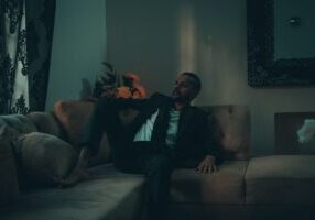 Professionally dressed person looking stressed while sitting in a minimalist, modern luxury living room, symbolizing the f...