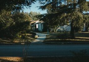 Sunny, clean suburban street that splits into a fork in the road, symbolizing the choice a homeowner faces between differe...
