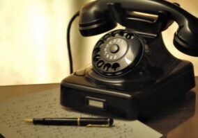 Vintage rotary phone and a modern smartphone sitting side-by-side on a clean surface, illustrating the contrast between ol...